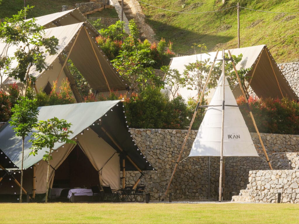 Aerial view of IKAN Glampsite’s glamping resort in Janda Baik, Malaysia, showing multiple luxury tents, landscaped grounds, and eco-friendly design, highlighting the difference between glamping and camping environments.