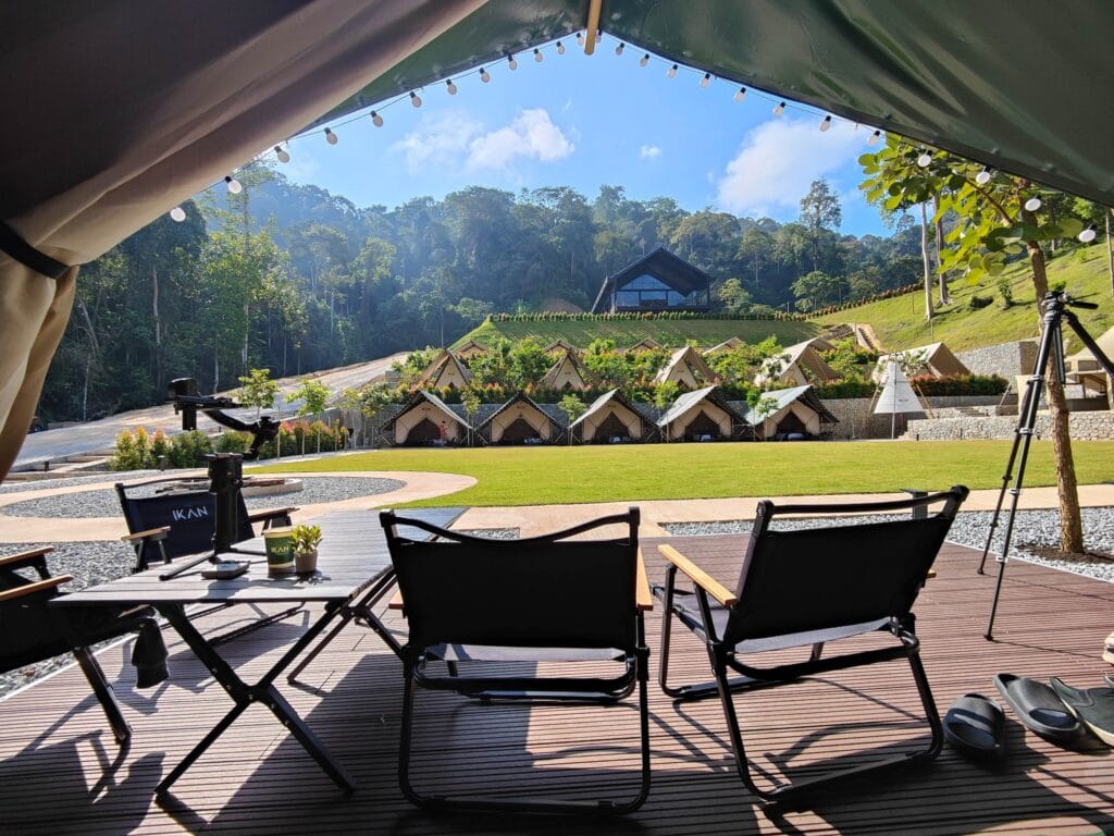 Weather-ready event setup at IKAN Glampsite with covered seating, open lawn, and rainforest surroundings in Janda Baik.
