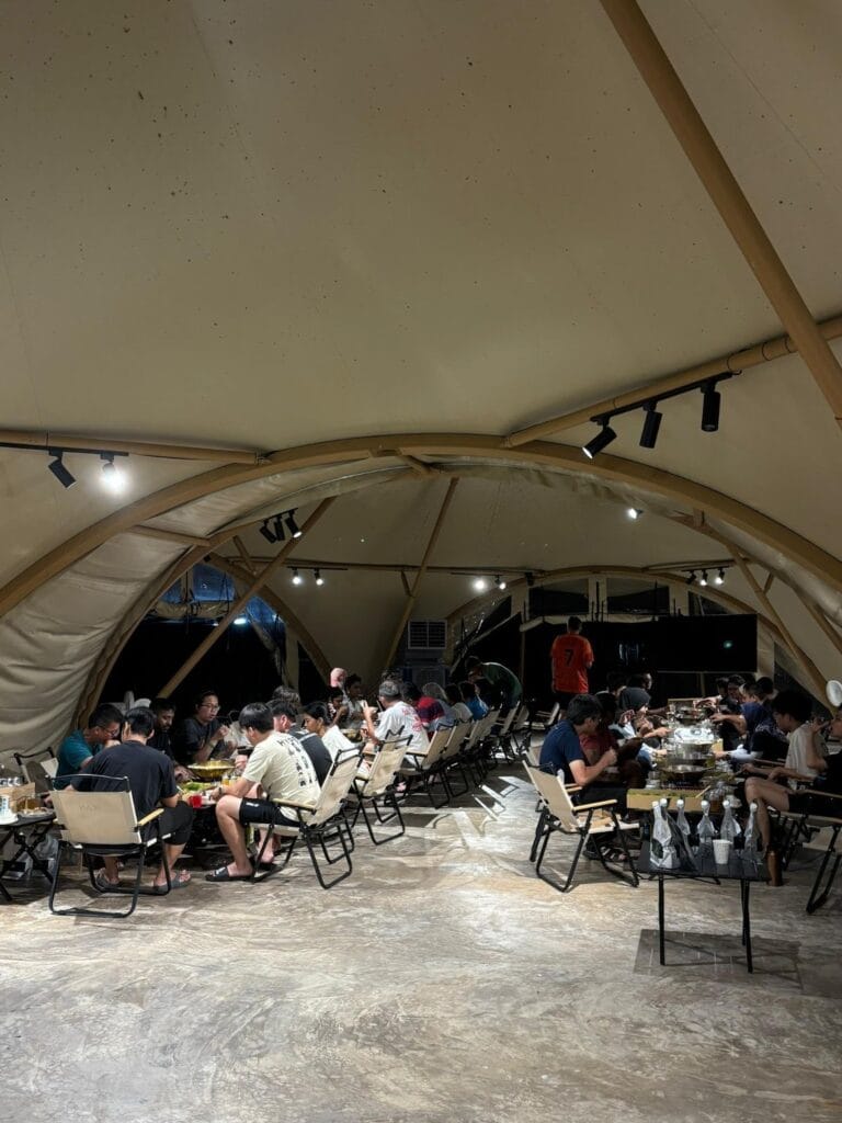 Corporate group gathering inside IKAN Glampsite’s spacious conference tent, used as an event hall and conference room for rent in nature.