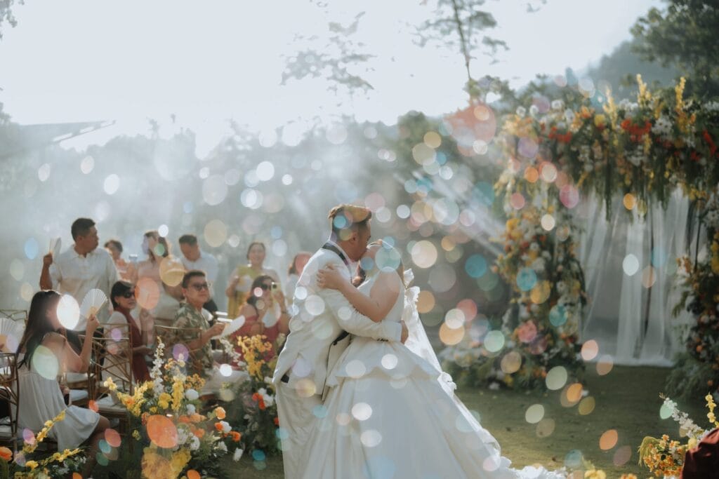 Couple celebrating an outdoor glamping wedding surrounded by guests and floral décor in nature