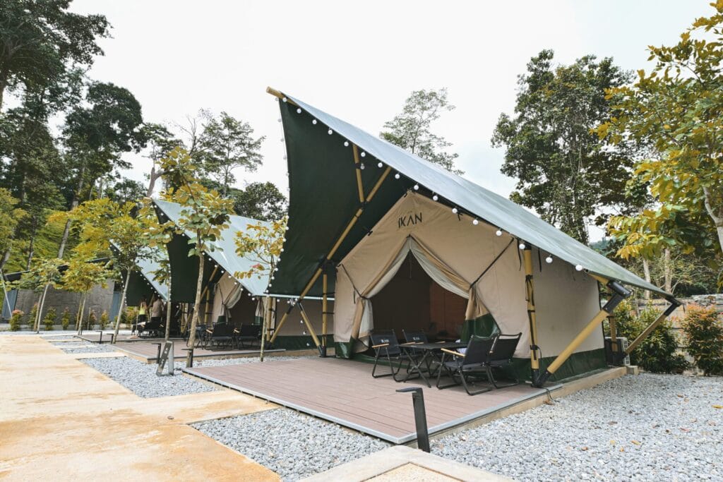 Spacious tents at IKAN Glampsite with outdoor seating surrounded by trees and nature in Janda Baik.