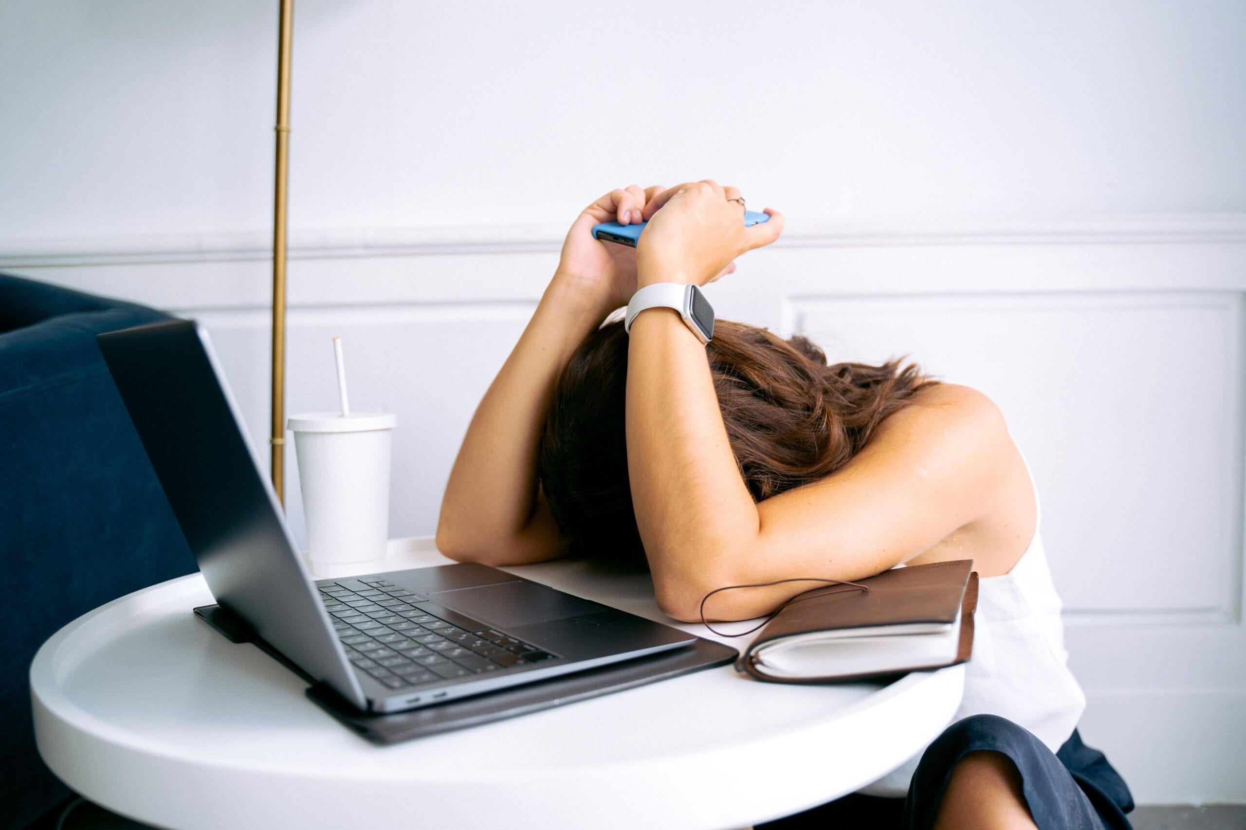 Person feeling mentally exhausted while using a laptop and smartphone, showing signs of technology overload.